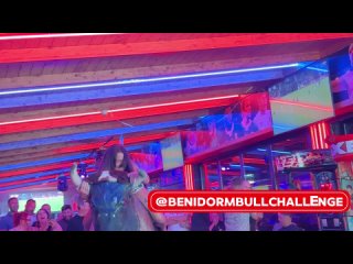 brunette girl in colorful spotted dress ride on benidorm mechanical bull 4k